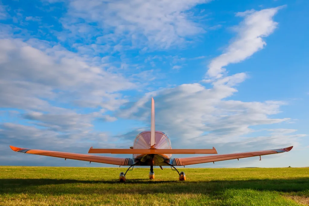 Light aircraft parked on a grass runway under blue skies, used for VFR flight training.